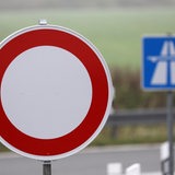 An einer Autobahnauffahrt wird mit einem weiß-roten Schild auf eine Sperrung hingewiesen. 