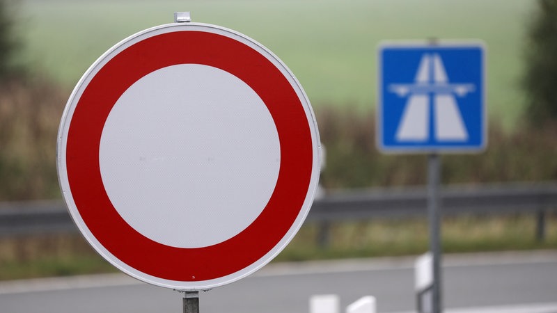 An einer Autobahnauffahrt wird mit einem weiß-roten Schild auf eine Sperrung hingewiesen. 