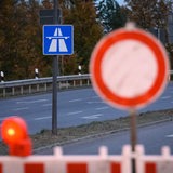 Eine Absperrbarke steht vor einem Autobahnschild.