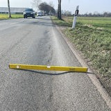 Eine Wasserwaage liegt liegt auf einer Straße über einer Vertiefung.