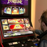 Ein Mann sitzt in einer Spielhalle an einem Spielautomat.