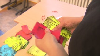 Eine Frau zählt Spielgeldscheine in einer Schule. 