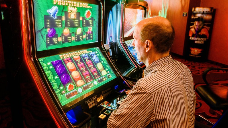 Ein Mann spielt in einer Spielhalle an einem Multigamerspielautomat