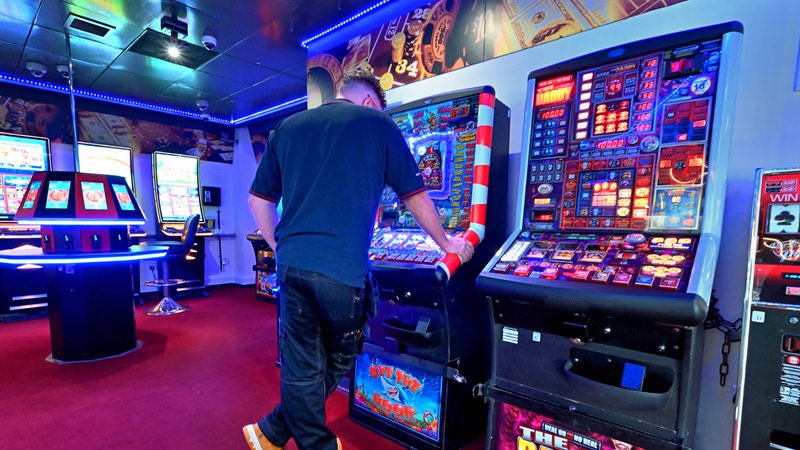 Ein Mann steht vor einem Automaten in einer Spielhalle