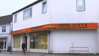 Eine Spielothek, vor dem eine Frau läuft.
