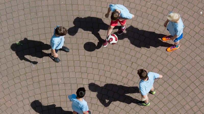 Schüler spielen Fußball auf einem Schulhof.