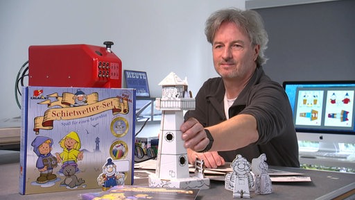 Boris Schimanski präsentiert einen Papierleuchtturm.