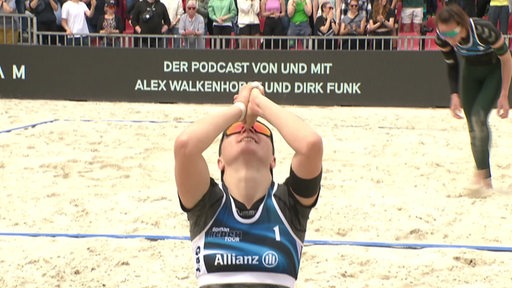 Eine Beachvolleyballerin fällt vor Freude nach dem Sieg auf die Knie. 