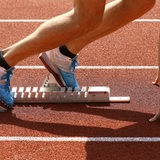 Beine und Schuhe eines Leichtathleten im Startblock