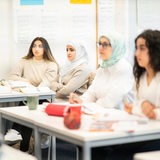 Vier Frauen sitzen an einem Tisch in einer Sprachschule.