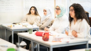 Vier Frauen sitzen an einem Tisch in einer Sprachschule.