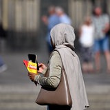 Eine schwarze Frau mit Kopftuch schaut auf ihr Handy.
