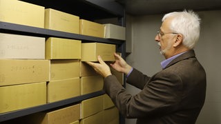 Archivleiter Konrad Elmshäuser zieht einen Karton aus einem Regal im Staatsarchiv Bremen.