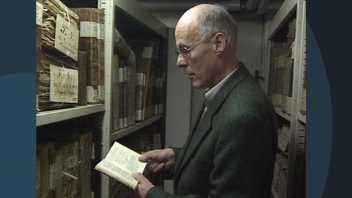 Ein Mann steht im Bremer Staatsarchiv und schaut ein Schriftstück an.