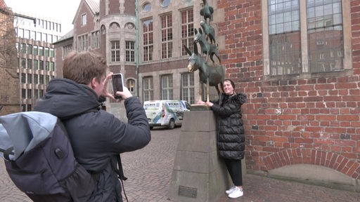Eine Frau lässt sich vor den Bremer Stadtmusikanten fotografieren.