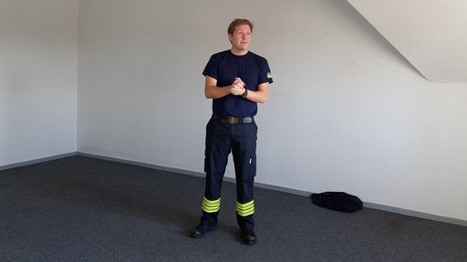 Ein Mann in Feuerwehr-Uniform steht in einem leeren Raum.