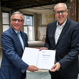 Andreas Bovenschulte (SPD, r), Präsident des Bremer Senats und Bürgermeister, und Johann Christian Jacobs, Vorstand der Joh. Jacobs & Co. Gruppe, halten bei einem Pressetermin den zuvor unterzeichneten Mietvertrag für das Stadtmusikanten- und Literaturhaus im ehemaligen Kontorhaus.
