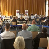 Menschen sitzen in einem Saal.