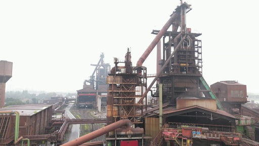 Es ist das Bremer Stahlwerk an einem grauen nebligen Tag zu sehen.