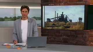 Moderator Janós Kereszti vor einem Bild des Bremer Stahlwerks.