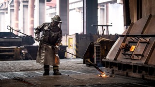 Stahlarbeiter schweißt Material in Schutzkleidung 