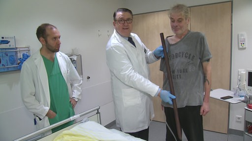 Zu sehen ist ein Cuxhavener im Krankenhaus, welchem die Stange, die ihn aufspiesst ha, von einem Arzt präsentiert wird.