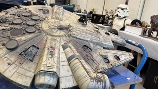 Ein Millenium Falcon-Modell vor verschiedenen anderen Star Wars-Exponaten.