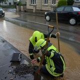 Nach unwetterartigen Regenfällen reinigen Feuerwehrleute Kanaldeckel. 