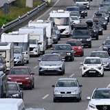 Zahlreiche Autos und Wohnwagen stehen in einem Stau auf einer Autobahn.
