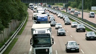 Eine Autobahn mit vielen Autos und Lastwagen die fast im Stau stehen.