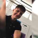 Ein Junge mit dunklen Haaren lächelt in die Kamera