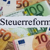 Auf vielen Geldscheinen liegt ein Zettel mit der Aufschrift "Steuerreform".