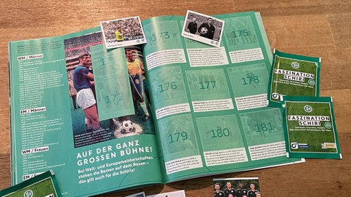 Ein aufgeklapptes Stickeralbum mit Bildern von Schiedsrichtern der Bundesliga.