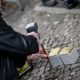 Eine Person bereitet bei der Verlegung der Stolpersteine für Ludwig M'Bebe Mpessa und Erika Emilie Mpessa in Berlin-Prenzlauer Berg den Pflaster vor. 