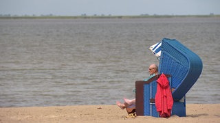 Ein Mann in einem Strandkorb am Strand.