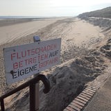 Ein Schild mit der Aufschrift "Flutschäden Betreten auf eigene Gefahr" weist am Strand der ostfriesischen Insel Wangerooge auf fehlenden Sand am Strand hin.