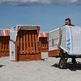 Zwei Männer bauen Strandkörbe auf.
