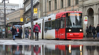 Eine Straßenbahn an der Haltestelle Domsheide in Bremen spiegelt sich in einer Pfütze.