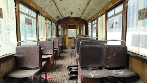 Blick in einen alten Waggon der Bremerhavener Straßenbahn mit braunen, dreckigen Sitzen.