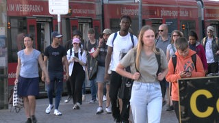 Viele Menschen steigen aus einer Straßenbahn.