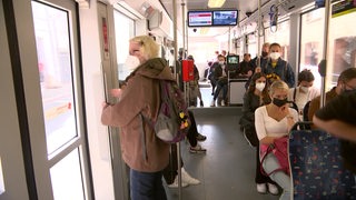 Viele Personen sitzen und stehen in einer Straßenbahn.