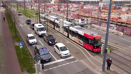 Zu sehen ist eine Straßenbahn und mehrere Autos in der Überseestadt.