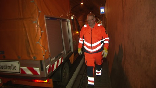 Ein Straßenkontrollwagen im Tunnel mit Warnblinkpfeil. 