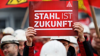 "Stahl ist Zukunft" steht auf dem Plakat eines Arbeiters bei einer Kundgebung der IG Metall.