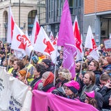 Rund 250 studentische Mitarbeiter halten bei einer Demonstration Banner und Fahnen in die Höhe.
