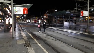 Zwei Personen laufen am Bremer Hauptbahnhof an den Haltestellen entlang.