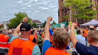Hafenarbeiter streiken in Bremerhaven mit Warnwesten vor der großen Kirche