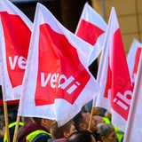 Demonstranten halten Fahnen der Gewerkschaft Verdi bei einer Kundgebung.