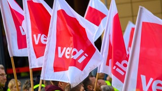 Demonstranten halten Fahnen der Gewerkschaft Verdi bei einer Kundgebung.