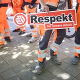 Bauarbeiter halten ein Schild "Respekt für unsere Arbeit" in den Händen